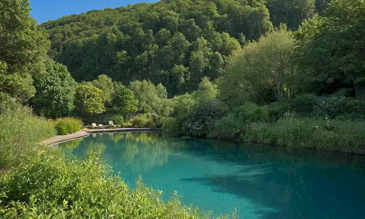 Aquí hay una descripción de la imagen de la cubierta: Un entorno sereno y natural con un cielo azul brillante, vegetación exuberante, suaves colinas, un lago tranquilo o piscina, unos pocos árboles, un sendero o un sendero, y un efecto gradiente sutil para evocar un sentido de tranquilidad y tranquilidad